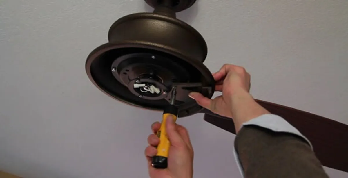 Electrician installing ceiling fan mounting bracket and fixture in Overland Park, KS