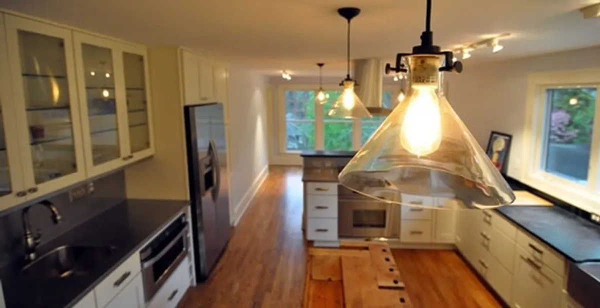Residential electrician installing modern indoor light fixture in a home in Overland Park, KS